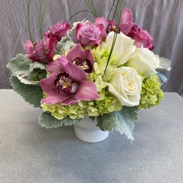 Pink and white floral arrangement in a white vase with arched stems