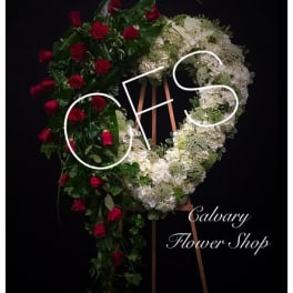 Heart-shaped floral wreath with red roses and white flowers on an easel
