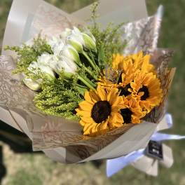 Bouquet of white tulips and yellow sunflowers in patterned wrap