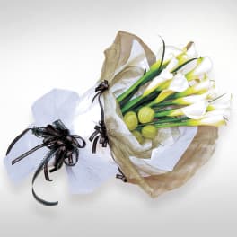 Bouquet of white calla lilies wrapped in tan and white paper
