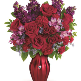 Red roses and purple flowers arranged in a red vase