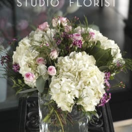 Pink roses and white hydrangeas arranged in a glass vase