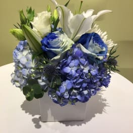 Blue and white floral arrangement in a white square vase