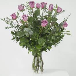 Pink roses in a clear glass vase with mixed greenery