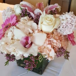 Pink and white floral arrangement in a square glass vase