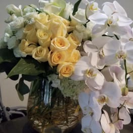Bouquet of pale yellow roses and white orchids in a glass vase