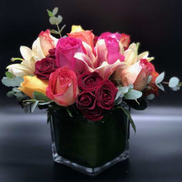 Bouquet of pink, red, and peach roses in a square glass vase