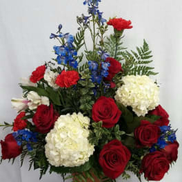Red roses, white hydrangeas, and blue flowers in a terracotta pot