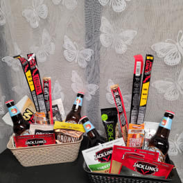 Two gift baskets filled with snacks and bottled drinks on a table