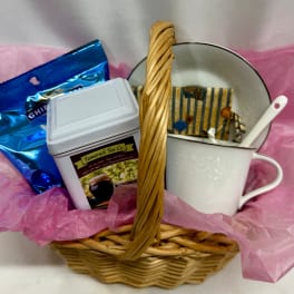 Gift basket with tea tin, blue package, teacups, and a spoon