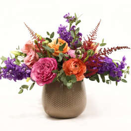 Colorful bouquet of roses and purple flowers in a gold vase