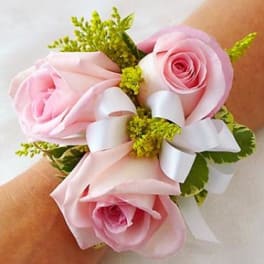 Pink rose wrist corsage with white ribbon and green accents