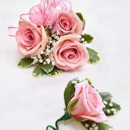 Pink rose corsage and boutonniere with small white filler flowers