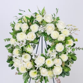 White rose and chrysanthemum wreath on a black stand