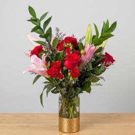 Red roses and pink lilies arranged in a glass vase