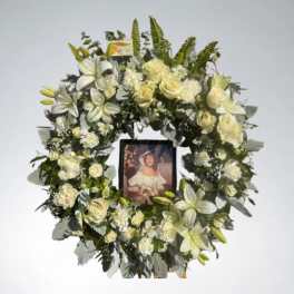 White floral funeral wreath with a framed photo in the center