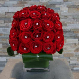 Red rose bouquet in a clear vase with green ribbon wrap
