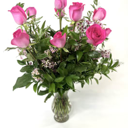 Pink roses in a clear glass vase with small filler flowers