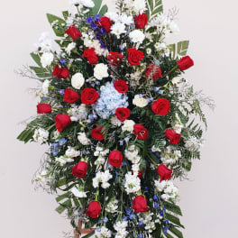 Large standing floral spray with red roses, white blooms, and blue accents