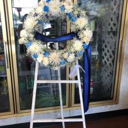 White and blue floral wreath on a standing easel with ribbon