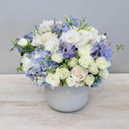 White and blue floral arrangement in a white vase