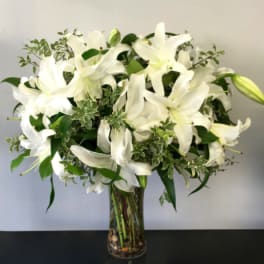 White lilies arranged in a clear glass vase