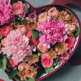 Heart-shaped box of pink and peach flowers
