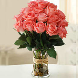 Pink roses arranged in a clear glass vase with pebbles