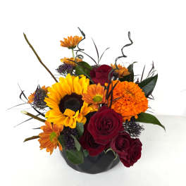 Bouquet of sunflowers, red roses, and orange mums in a black vase