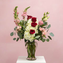 Red roses and white hydrangeas in a clear glass vase