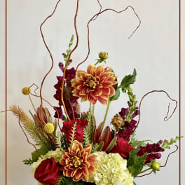 Mixed floral arrangement in a glass vase with red, orange, and white blooms