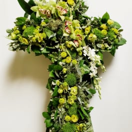 Green floral cross on an easel with white orchids and yellow blooms