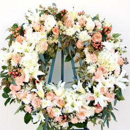 Large floral wreath with white lilies, peach roses, and pink berries