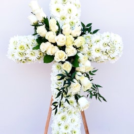 White floral cross with roses and daisies on a stand