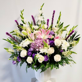Large bouquet of pink lilies, white roses, and purple flowers in a white vase