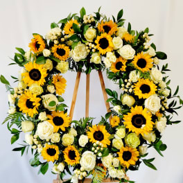 Large floral wreath with sunflowers and white roses on a wooden stand