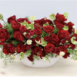 Red roses and pale green flowers in a white bowl vase