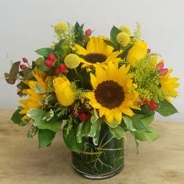 Sunflower and yellow rose arrangement in a glass vase