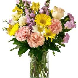 Mixed bouquet of yellow, pink, and white flowers in a clear glass vase