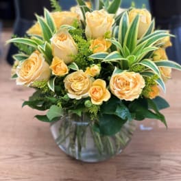 Peach roses in a clear glass vase with variegated foliage