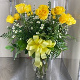 Yellow roses in a clear glass vase with a yellow ribbon