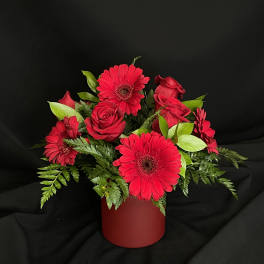 Red gerbera daisies and roses in a red vase