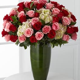 Bouquet of red and pink roses in a tall green glass vase