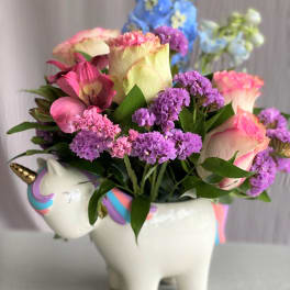 Pink and purple flowers arranged in a unicorn-shaped ceramic container