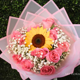 Pink rose bouquet with a sunflower and baby's breath wrapped in pink paper