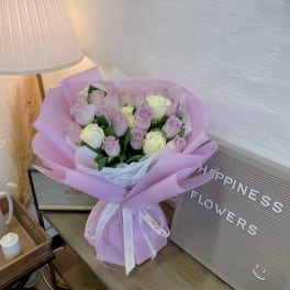 Bouquet of pale pink and cream roses wrapped in lavender paper