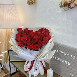 Bouquet of red roses wrapped in white paper with ribbon