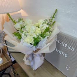 White rose bouquet wrapped in cream paper with a gray ribbon