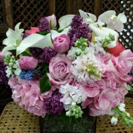 Pink and white floral arrangement in a square glass vase
