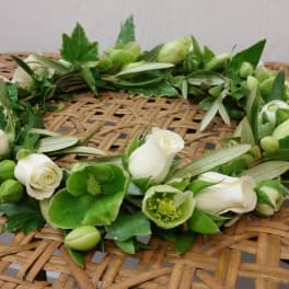 White rose and green flower crown on a woven surface